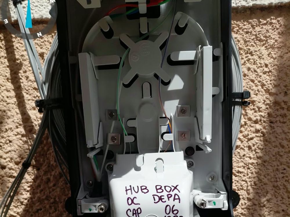 CTO montada en fachada y abierta, con la bandeja de empalme y el splitter rotulados.